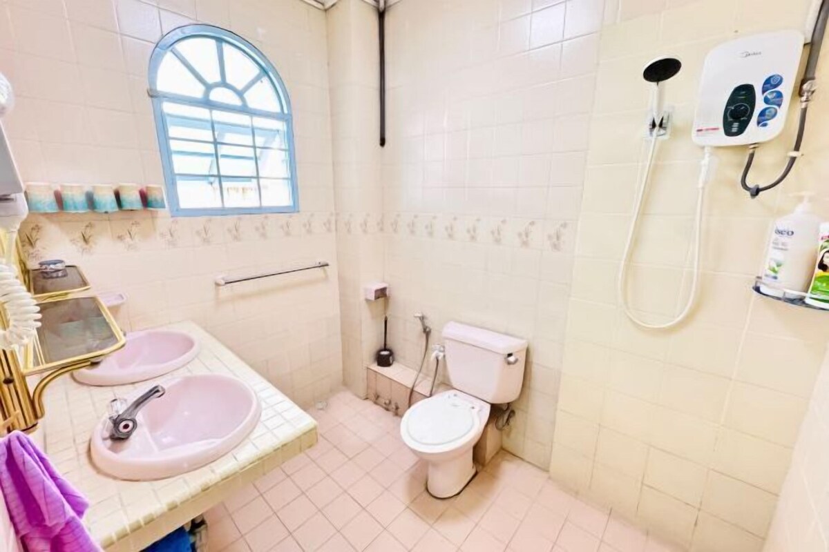 A small bathroom with two sinks, a toilet, a shower, and a window.