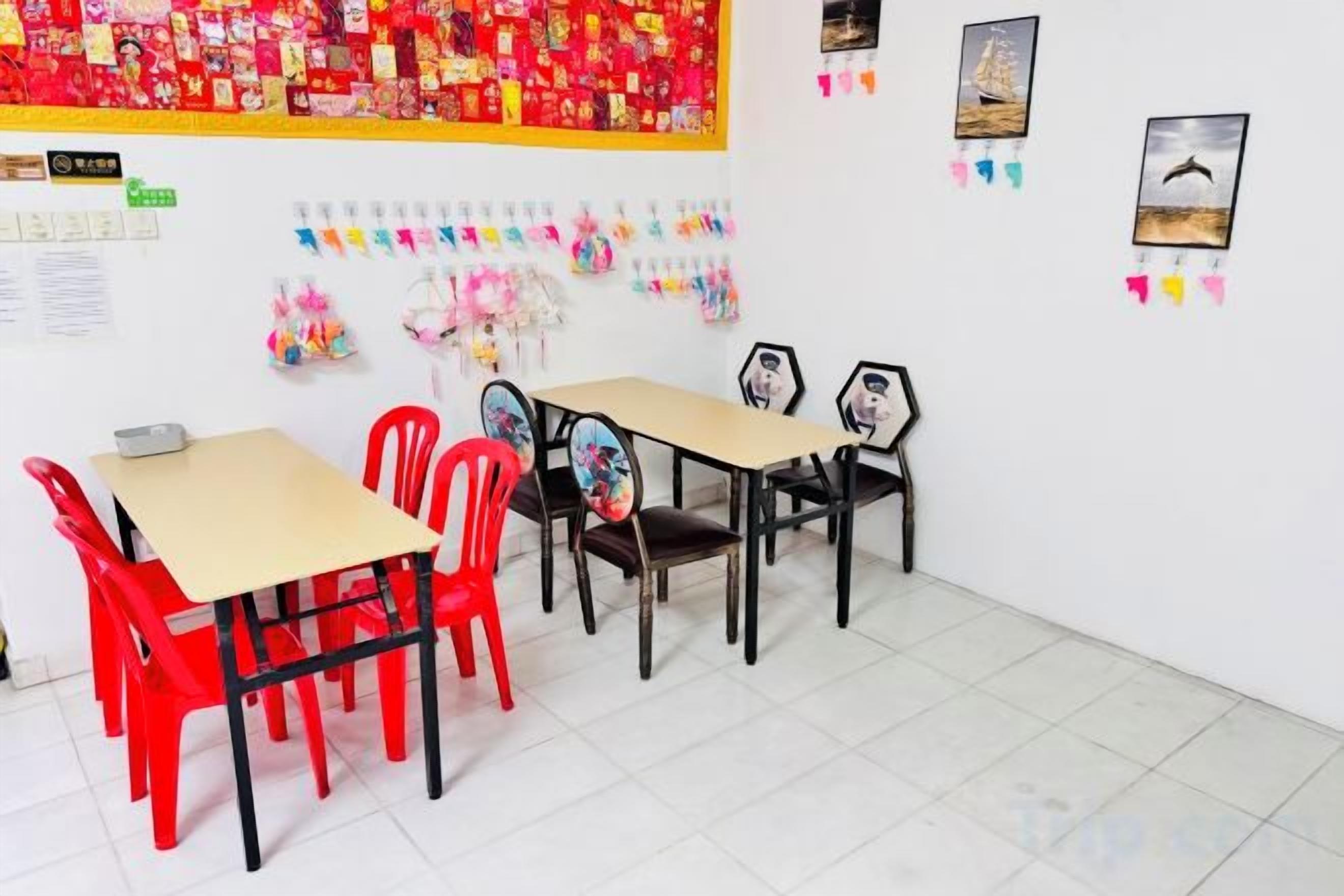 A classroom with tables and chairs, educational posters, and a large red poster on the wall.