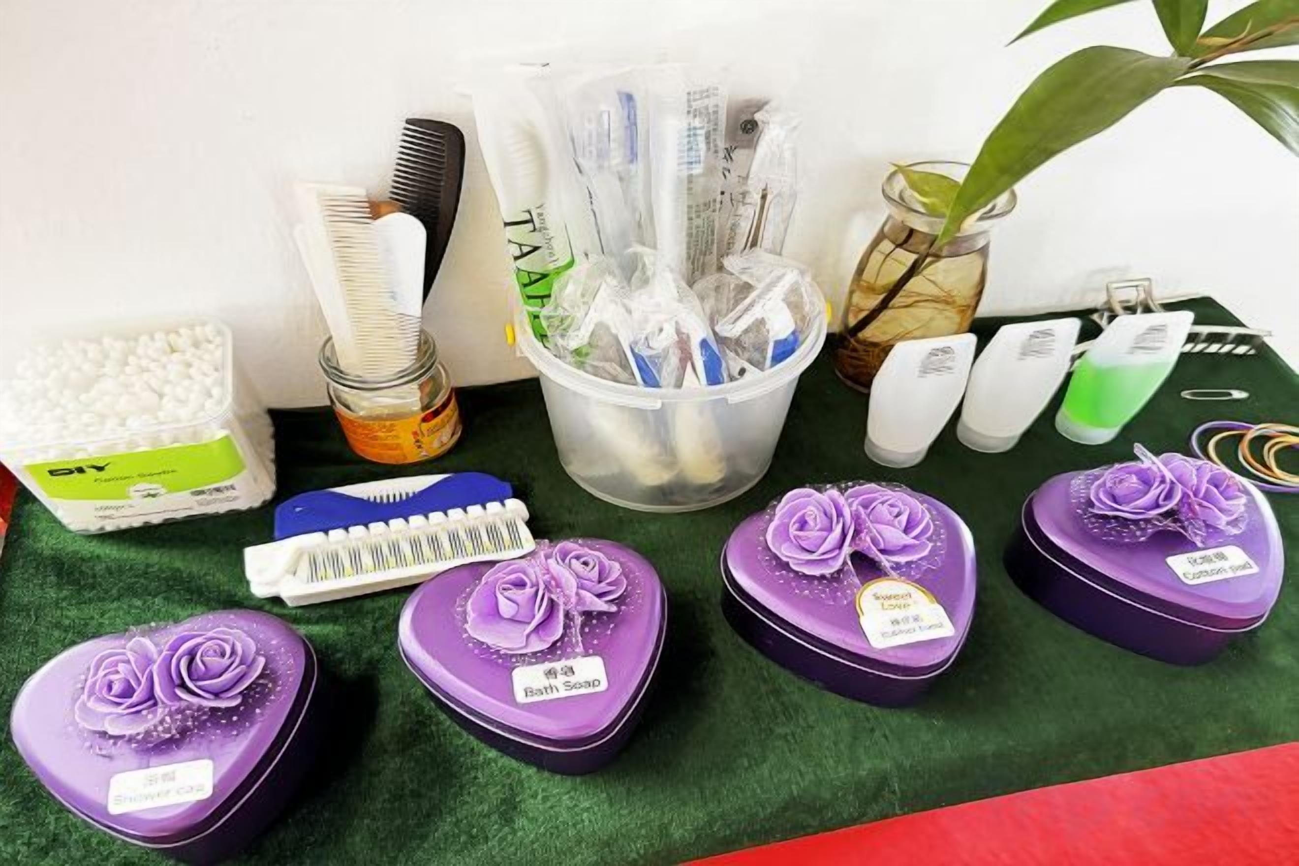 Un conjunto de artículos de tocador, incluyendo un peine, un cepillo para el cabello y varias botellas, junto con varios recipientes pequeños morados etiquetados 'Bath Soap'.