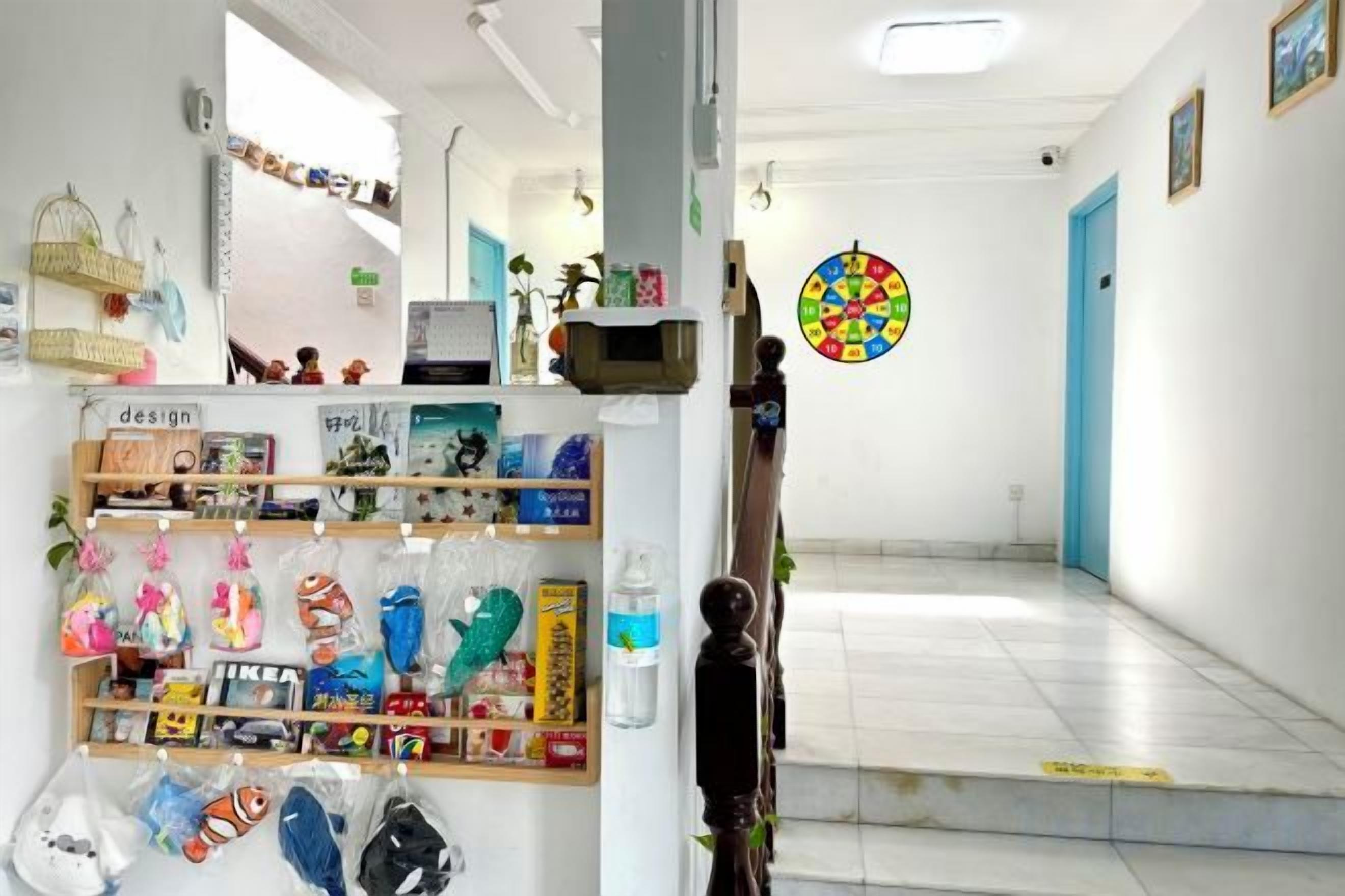 A hallway with a display of various items on shelves, a door with a colorful circular decoration, and a tiled floor.