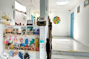 A hallway with a display of various items on shelves, a door with a colorful circular decoration, and a tiled floor. - Backyard Garden Villa (Petaling Jaya)