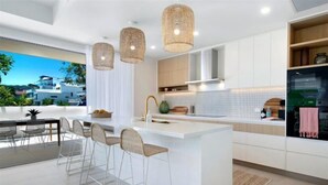 Una cocina moderna con una isla central, taburetes de bar e iluminación colgante.