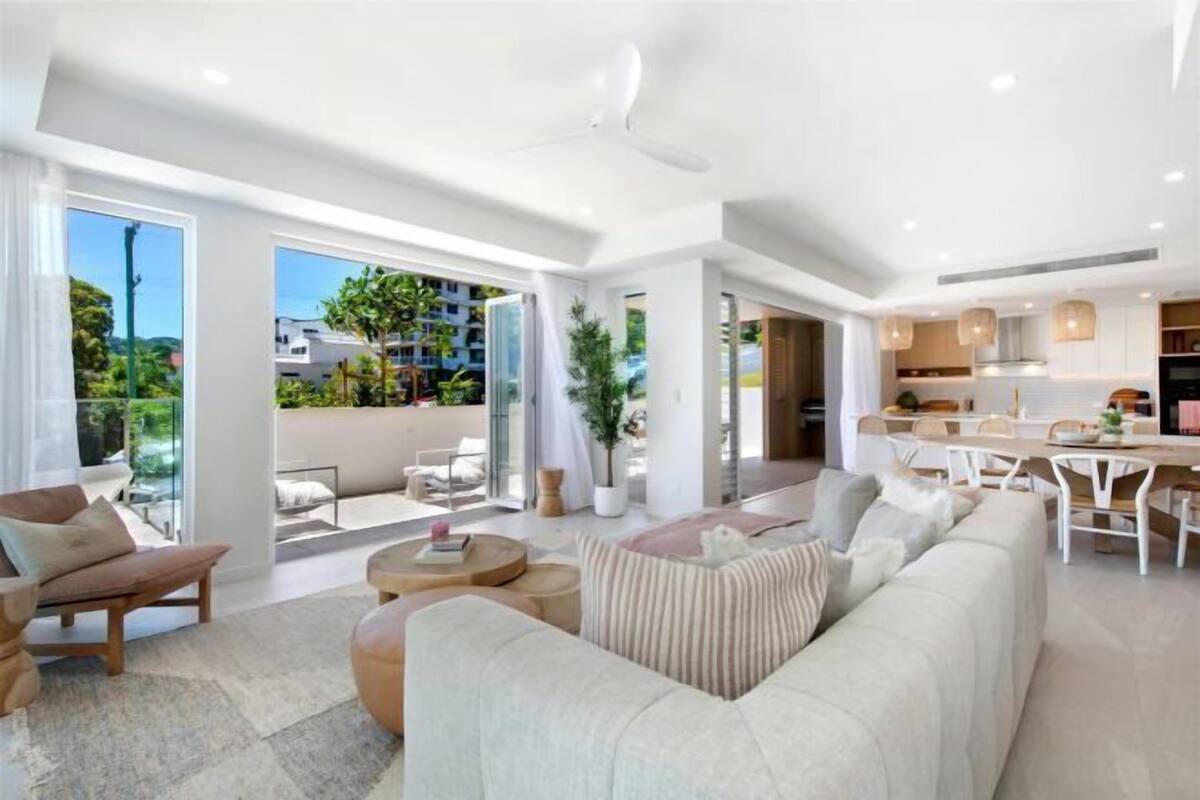 A modern living room with a sofa, coffee table, and a dining area with a table and chairs.