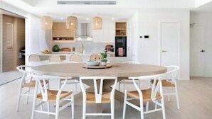 Una cocina moderna con armarios blancos, una mesa redonda de comedor e iluminación colgante.