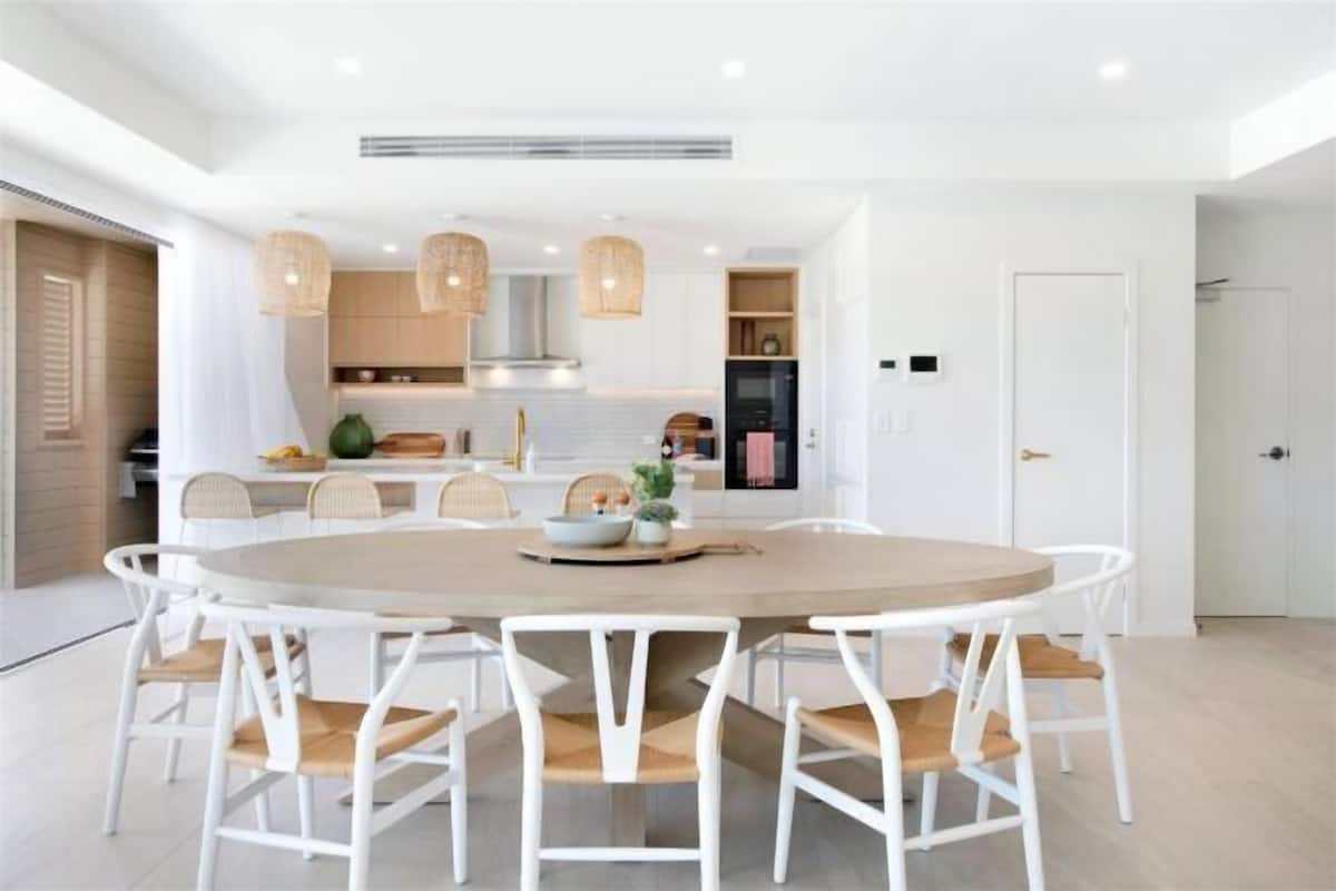 A modern kitchen with white cabinetry, a round dining table, and pendant lighting.