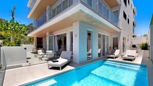 Un edificio moderno con piscina, mobiliario exterior y cielo despejado.