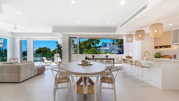 Una cocina moderna con una isla central, armarios blancos e iluminación colgante.