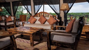 An outdoor seating area with wooden furniture and a view of the landscape. - Seregenti Kifaru Tented Lodge (Serengeti)