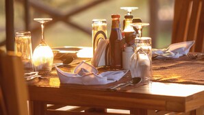 A dining table set with various glassware, bottles, and utensils, suggesting a formal dining experience. - Seregenti Kifaru Tented Lodge (Serengeti)