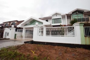 A residential property with a gated entrance, a driveway, and a well-maintained lawn. - Natol Homestay - Sydney Batu Kawa Mjc New Townships (Kuching)