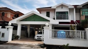 A modern two-story house with a covered driveway and a white fence.