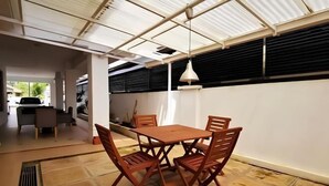 A dining area with a table and chairs, a hanging light fixture, and a view of the outside.