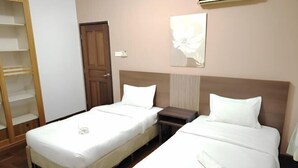 A hotel room with two beds, a wardrobe, a door, and a wall-mounted air conditioner.