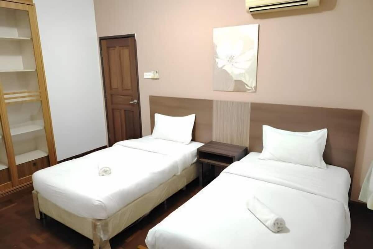 A hotel room with two beds, a wardrobe, a door, and a wall-mounted air conditioner.