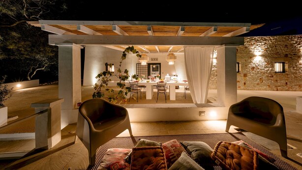 An outdoor dining area with a pergola, a table set for dining, and two chairs.