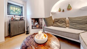 A cozy living room with a wooden coffee table, a sofa with patterned cushions, and a fireplace.