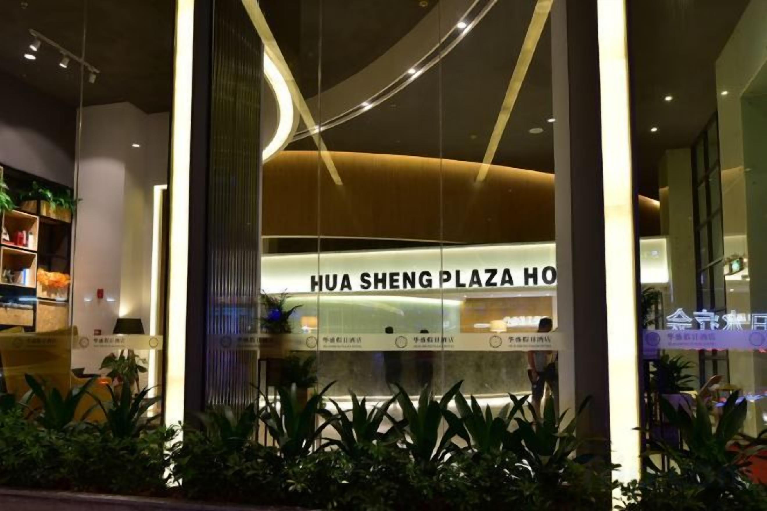 Exterior del Hotel Hua Sheng Plaza, con un diseño moderno, amplios ventanales de vidrio y una entrada bien iluminada.