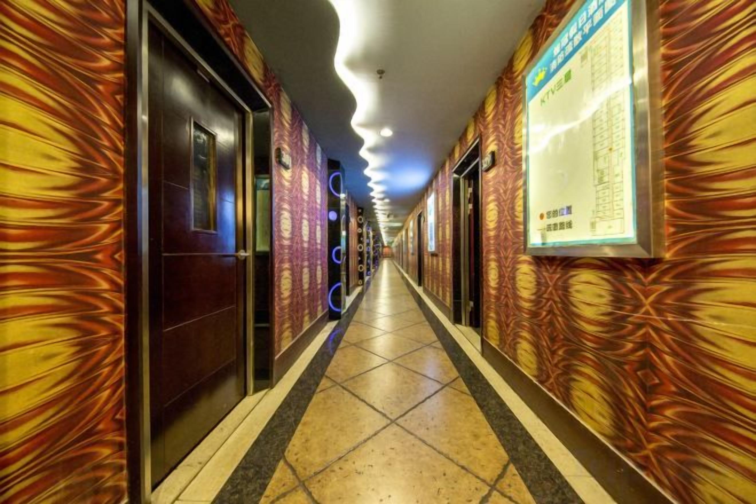 Un corridoio d'albergo con pareti, porte e pavimento piastrellati decorati.