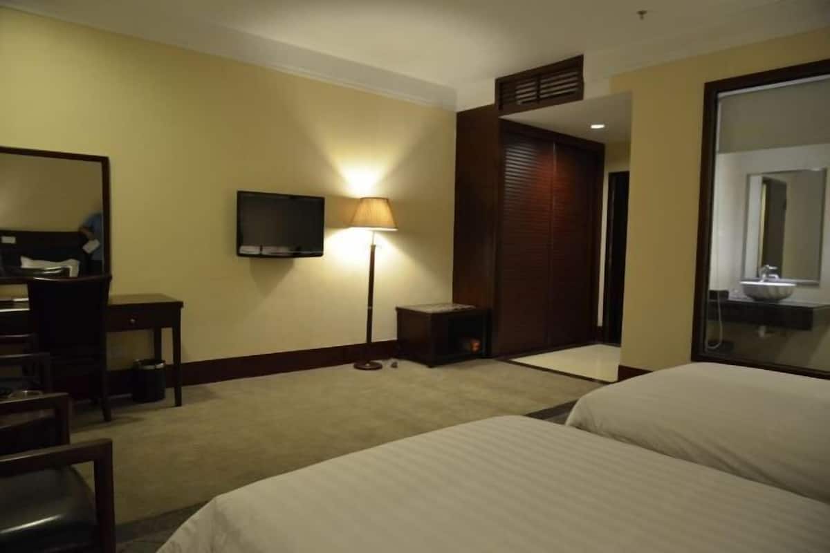 Een hotelkamer met een bed, een bureau met stoel, een televisie en een lamp.