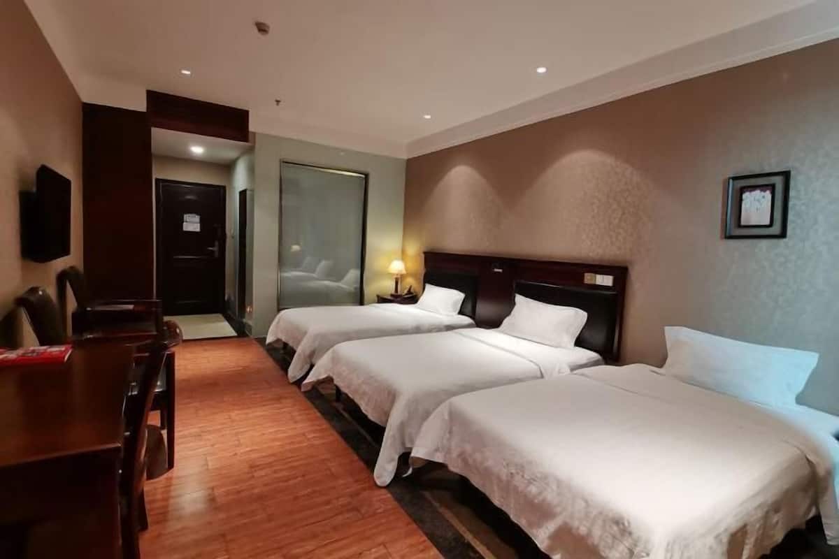 Een hotelkamer met twee bedden, een bureau en een televisie.