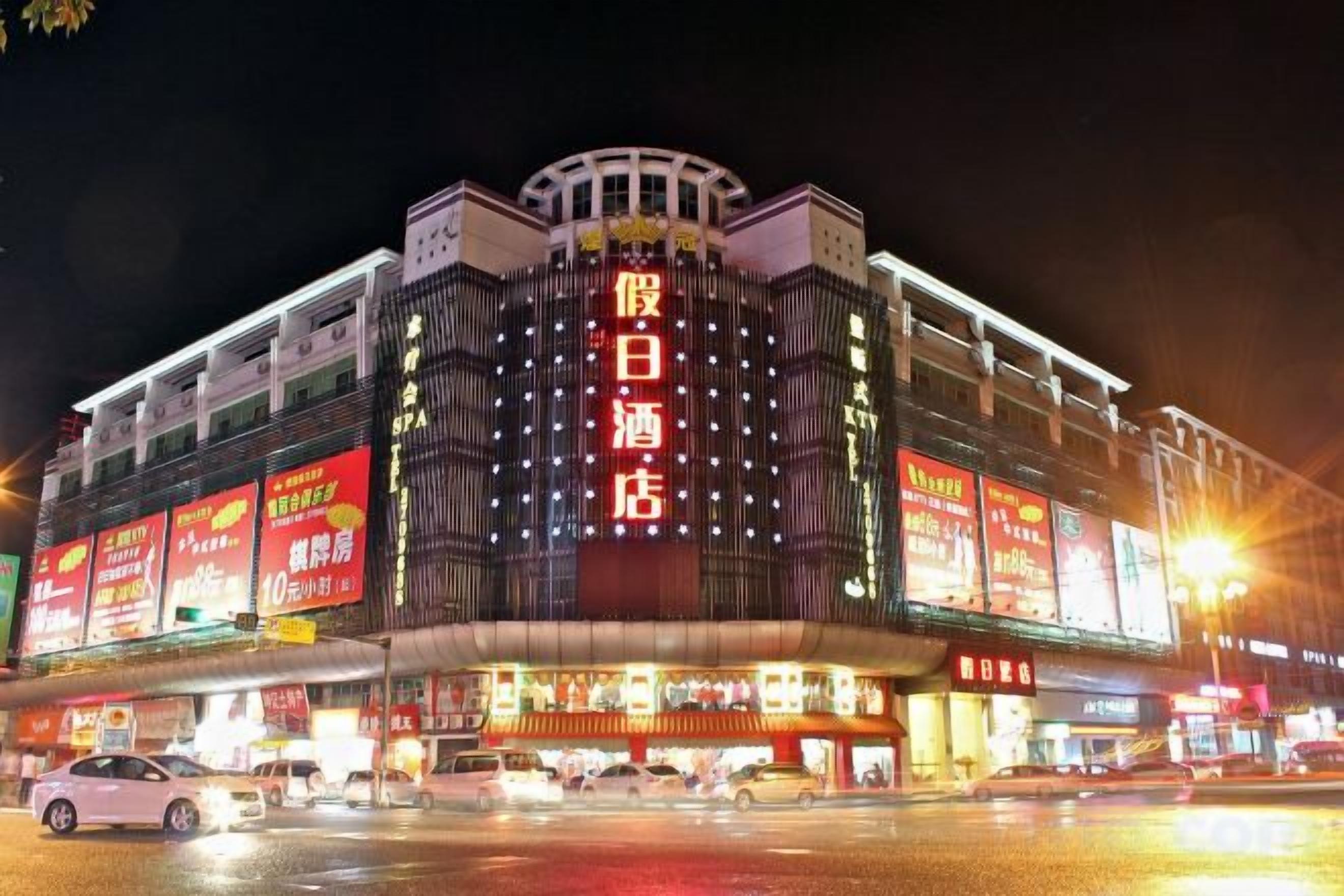 A multi-story building with illuminated signage, a prominent entrance, and a covered area with seating.