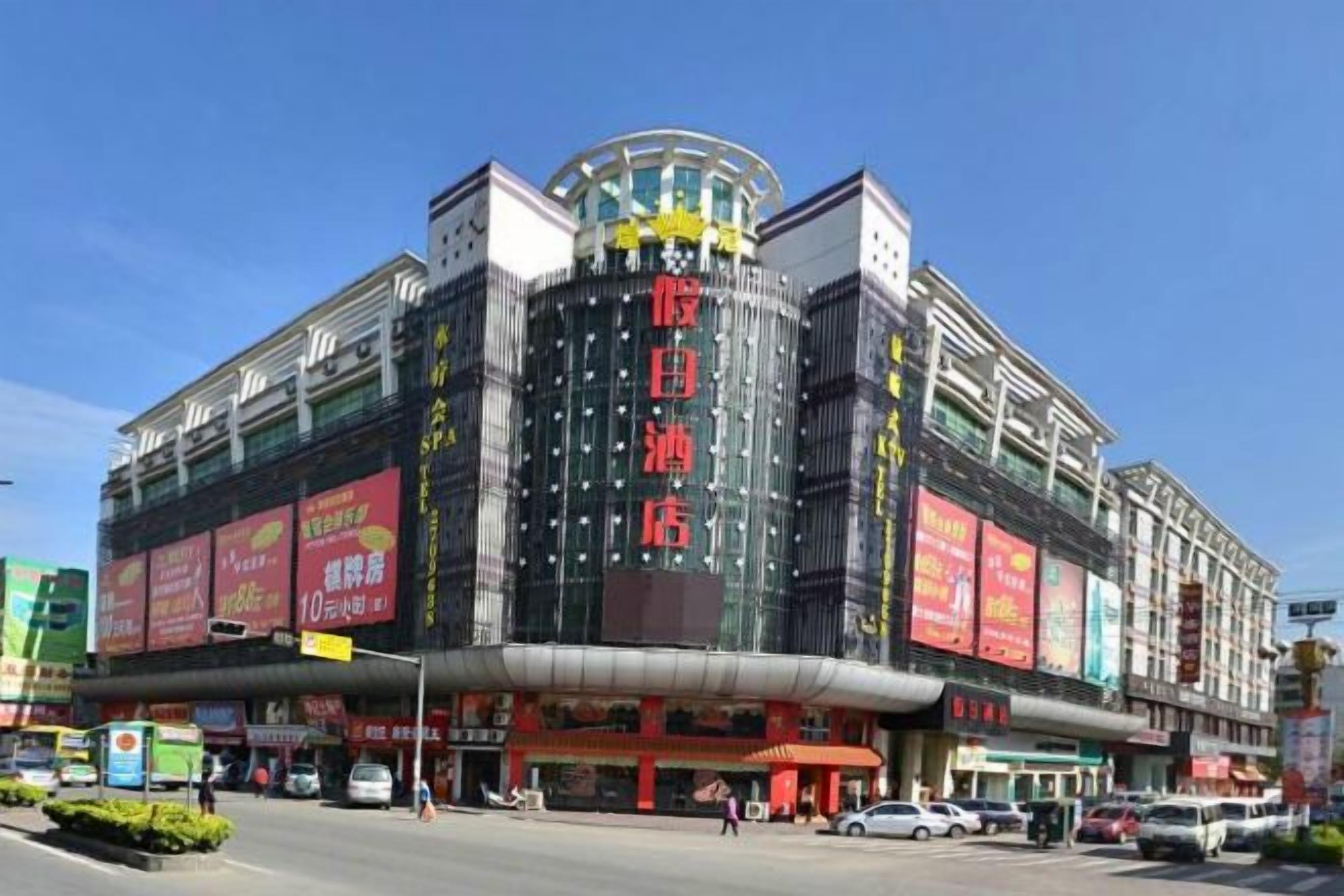 A multi-story building with large signage, likely a hotel or commercial complex, featuring a prominent entrance and multiple levels.