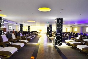 A hotel lobby with rows of seating, a reception area, and a large pillar with circular patterns.