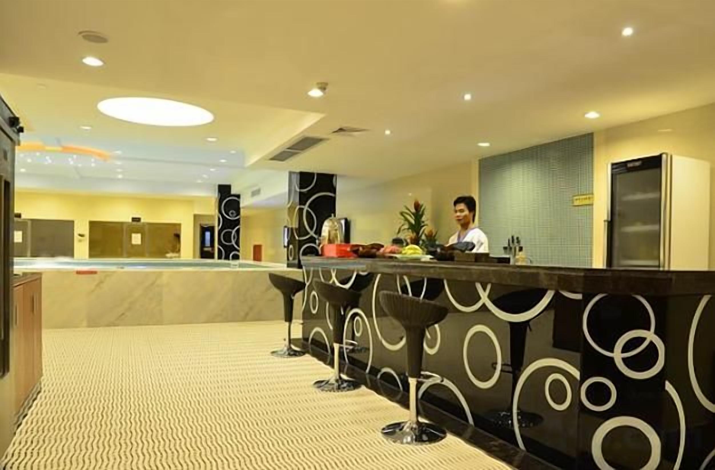 A hotel lobby with a reception desk, a bar area, and a patterned floor.