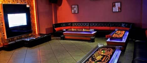 Quarto com televisão, sofá e mesa com almofada decorativa.