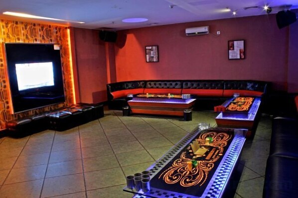 A room with a television, a sofa, and a table with a decorative table runner.
