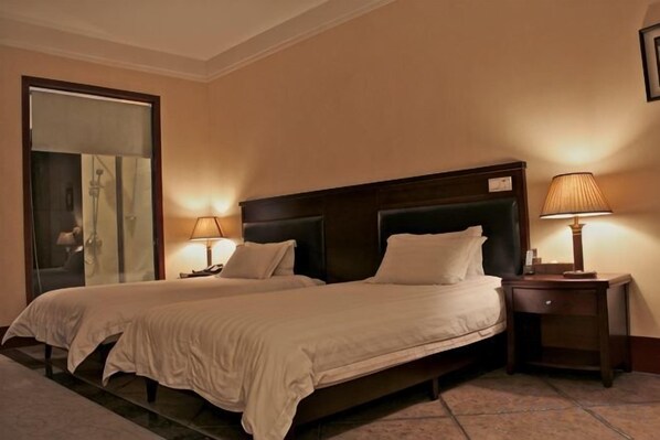 A hotel room with two beds, a large mirror, and two bedside lamps.