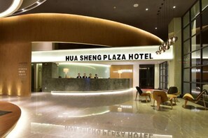 The interior of Hua Sheng Plaza Hotel with a reception desk, seating area, and a modern design.