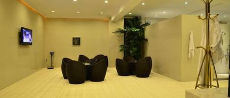 A hotel lobby with a reception desk, seating area, and a large plant.