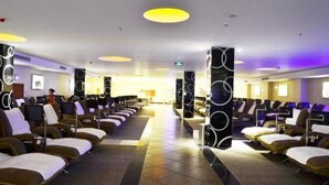 A modern hotel lobby with rows of seating, a central reception area, and a bright, circular ceiling light fixture. - Huangguang Holiday Hotel (Kaiping)