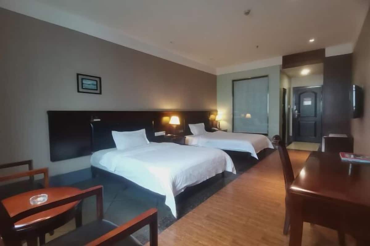 Een hotelkamer met twee bedden, een houten bureau en een stoel.
