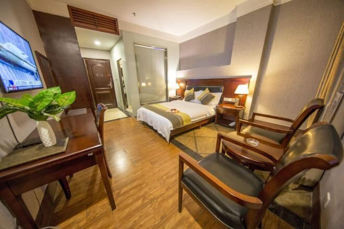 Een hotelkamer met een bed, een bureau, een stoel, een televisie en een plant.