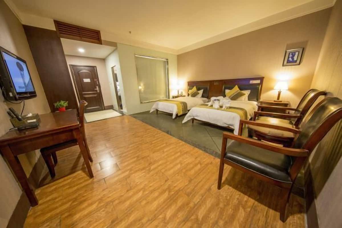 Een hotelkamer met twee bedden, een bureau, een televisie en een zithoek.
