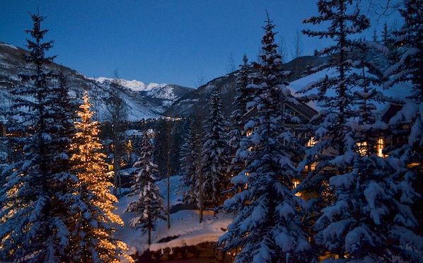 A snow-covered mountain landscape with a lit building in the foreground.