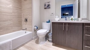 A modern bathroom with a bathtub, toilet, and vanity with cabinets. - Private Downtown Seaport Apt with Pool (Boston MA)