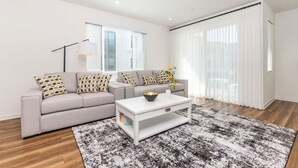A modern living room with a grey sofa, white coffee table, and a black and white rug. - Private Bedroom With Bathroom Central Location (Santa Ana)