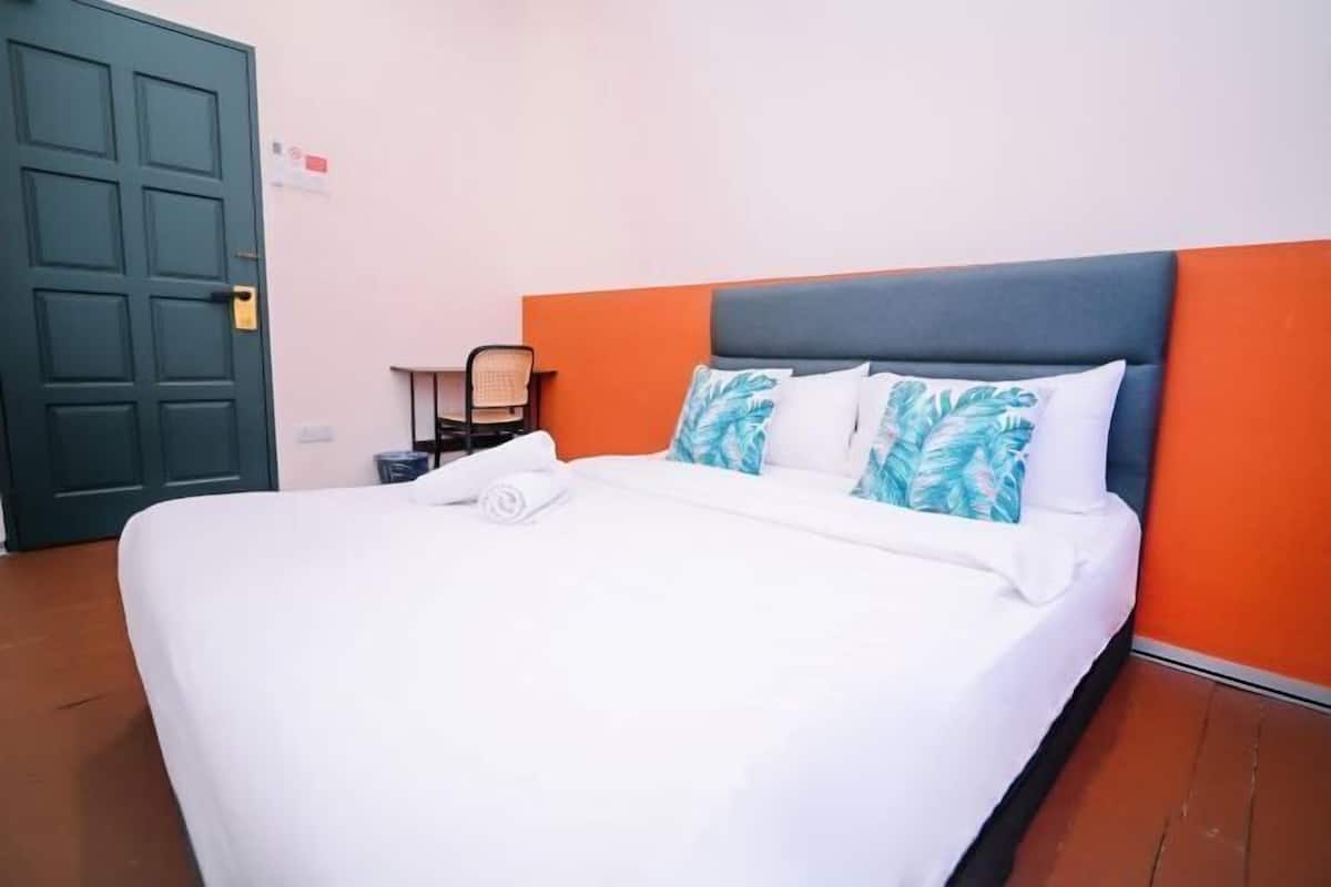 A hotel room with a bed, a desk, and a chair.
