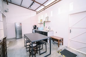 A compact kitchen with a refrigerator, a sink, and a dining table with chairs. - Swing & Pillows @ 75 Chulia St, Georgetown Penang (George Town)