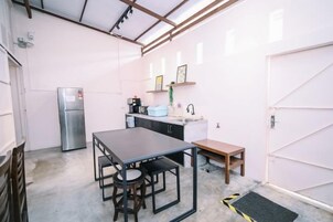 A compact kitchen with a refrigerator, a sink, and a dining table with chairs.