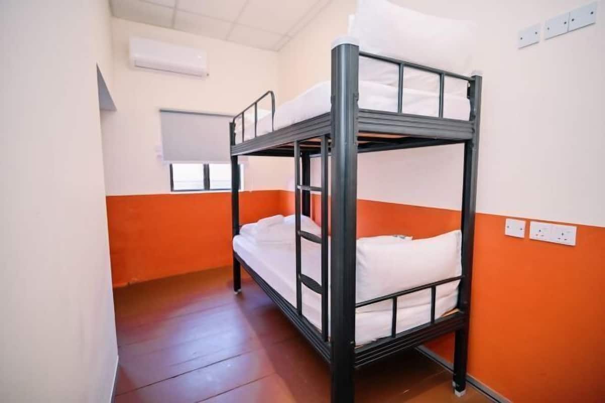 A bunk bed room with orange walls and white bedding.