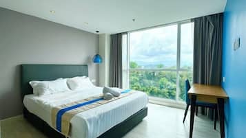 A modern hotel room with a large bed, a desk, and a view of the outdoors.
