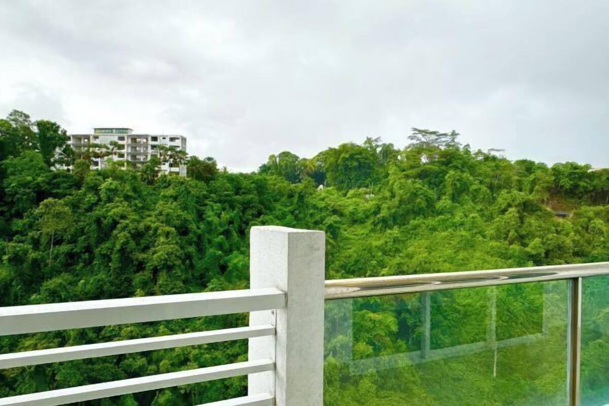 Un edificio moderno con un balcone in vetro affacciato su una fitta foresta verde.