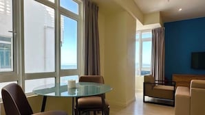 A modern living room with a glass table, two sofas, and large windows offering a view. - M Centro City Centre @ Gaya Street by Ssvc (Kota Kinabalu)