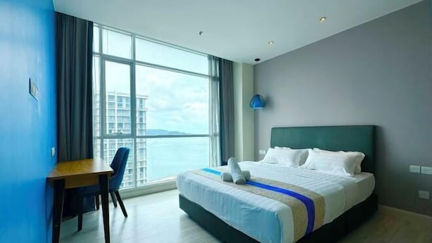 A hotel room with a bed, a desk, and a large window offering a view of a building and the sky. - M Centro City Centre @ Gaya Street by Ssvc (Kota Kinabalu)