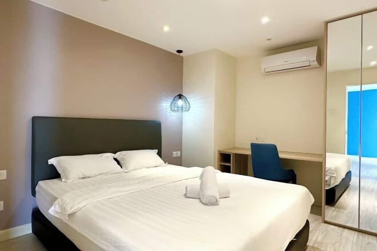 Una camera d'albergo con un letto, una scrivania, una sedia, uno specchio e un condizionatore d'aria.