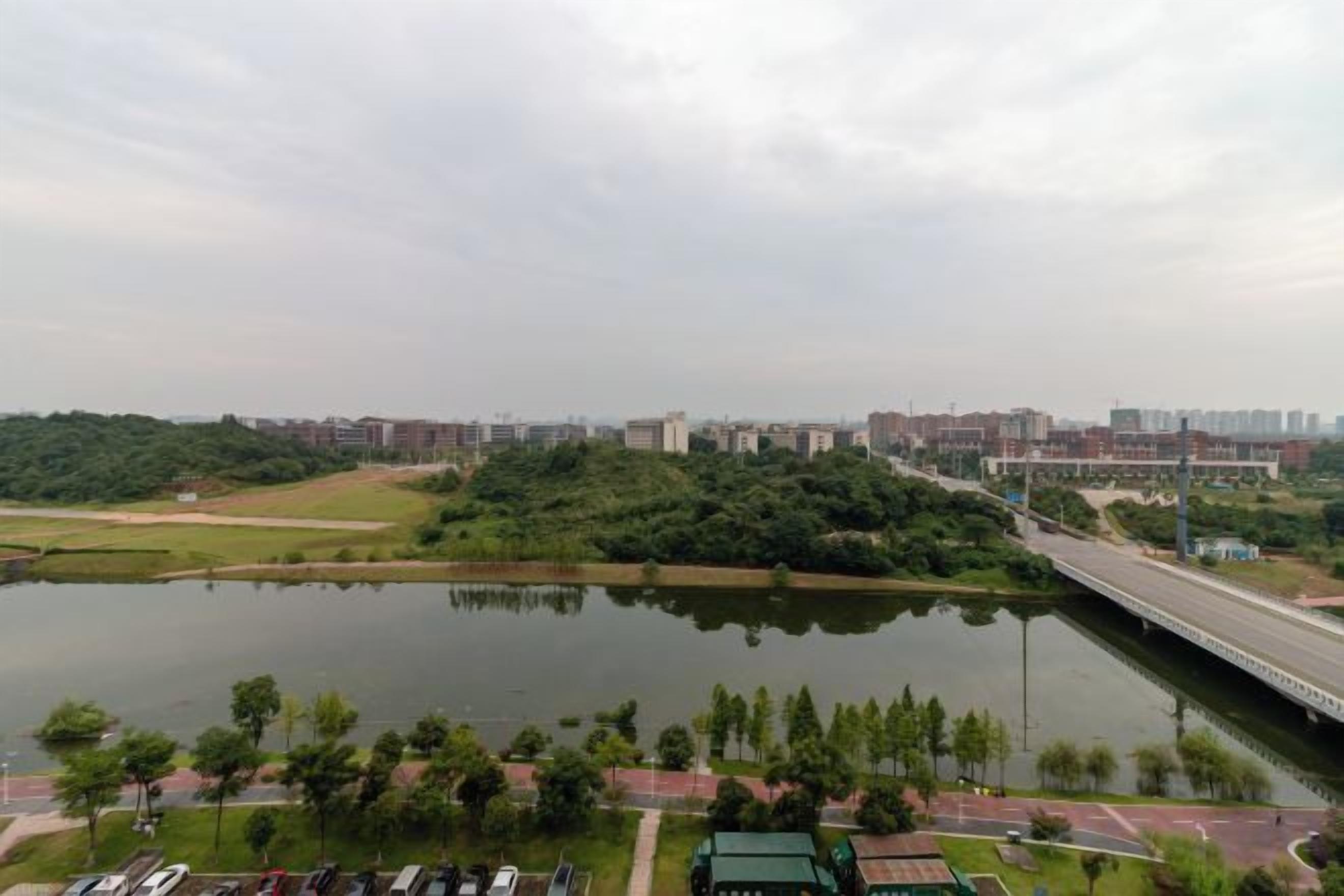 A river with a bridge, a parking lot, and buildings in the background.